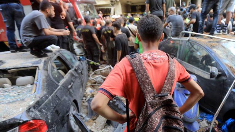 Gente reunida frente a un edificio bombardeado en un suburbio del sur de Beirut, Líbano.