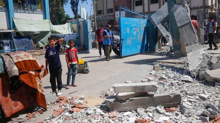 Varias personas examinan los daños causados por el bombardeo de una escuela en el centro de Gaza.