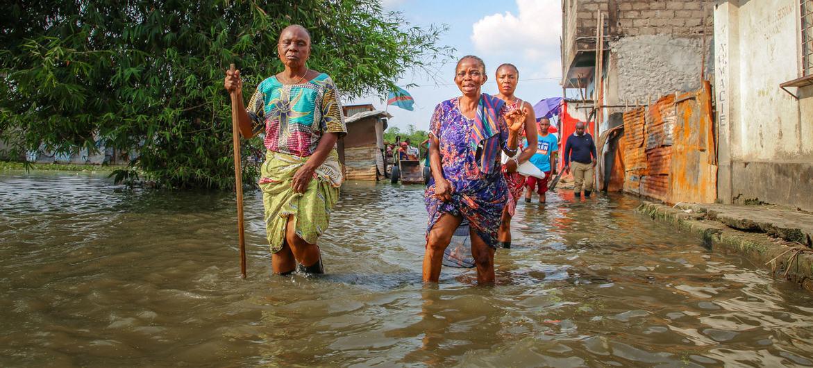 $!Varias mujeres vadean las aguas de una inundación en un barrio de Kinshasa, RD del Congo.