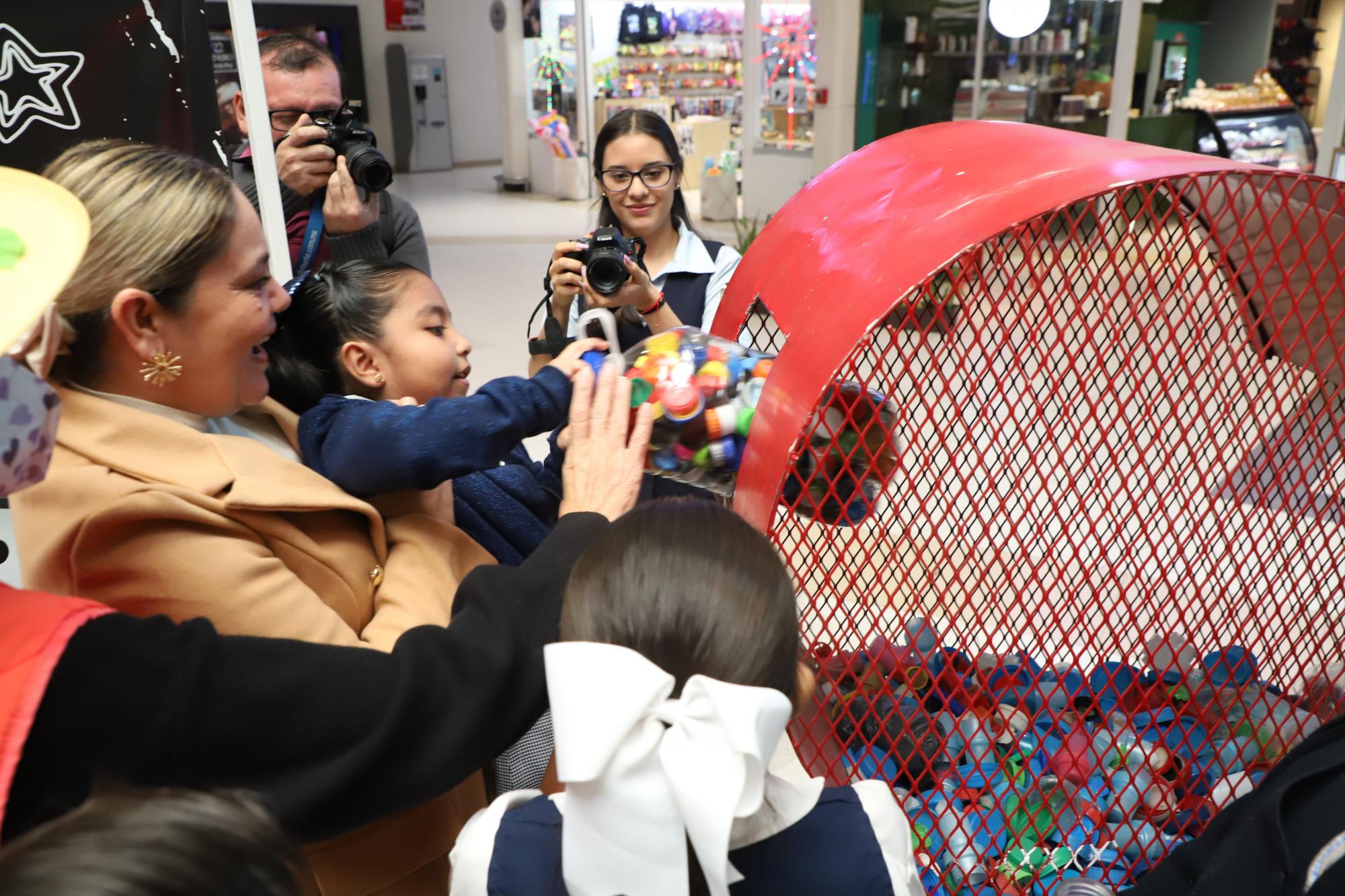 $!María Teresa Apodaca, presidenta del DIF Municipal, ayuda una pequeña a realizar su donativo en un corazón instalado en una de las áreas de la plaza comercial.