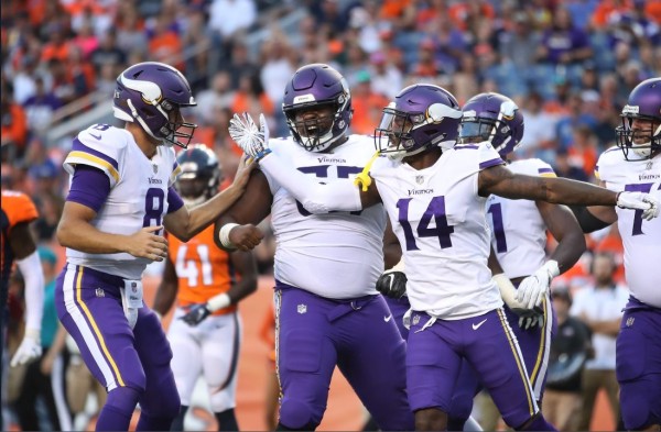 Kirk Cousins (izquierda) celebra una jugada con sus compañeros de los Vikings de Minnesota.