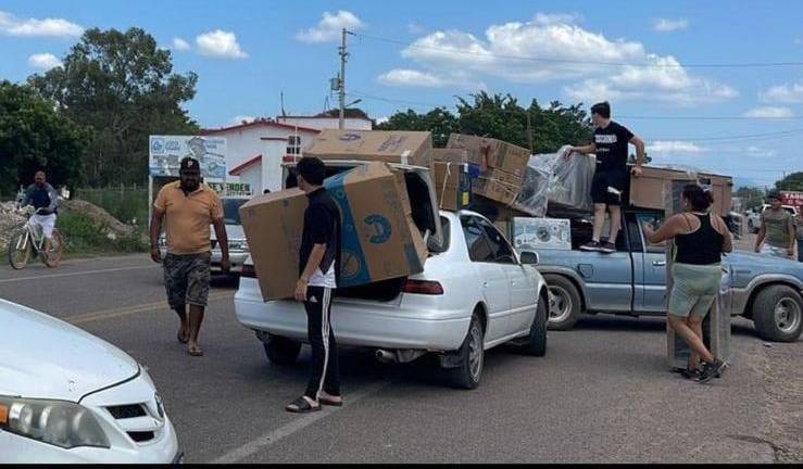 Personas se llevan artículos de mueblería de un tráiler tras los enfrentamientos en Quilá, al sur de Culiacán.