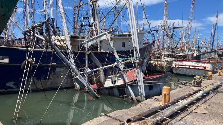 Barcos hundidos, quemados y oxidados siguen varados en el muelle.