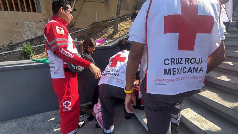 Personal de Cruz Roja atiende a una mujer cuando acudía al templo de La Lomita, en Culiacán.