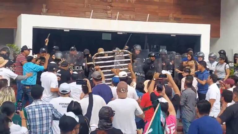 Afuera del recinto legislativo, jóvenes y trabajadores del Poder Judicial se enfrentan a la policía antimotines.