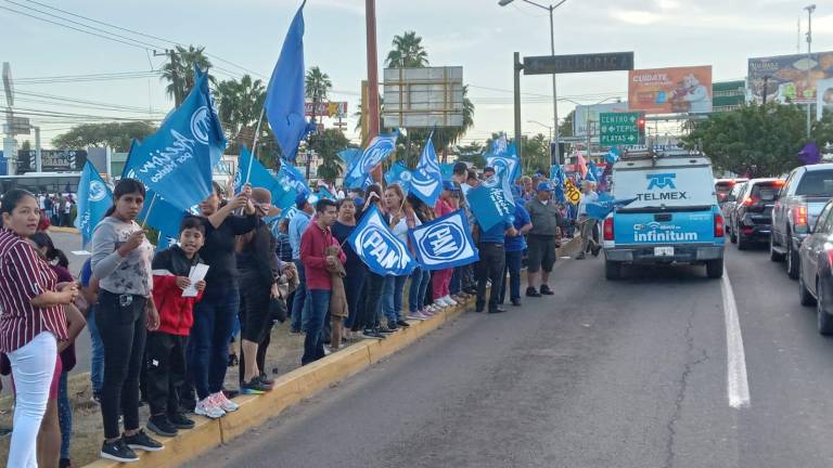 Un grupo de personas con playera azul y banderines entregaban volantes a las personas.