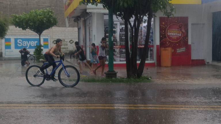 Niños se bañan en la lluvia pero procuran protegerse de los truenos.