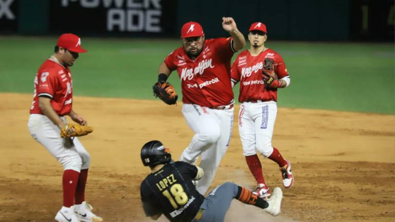 Carlos Muñoz salta sobre Irving López en jugada apretada en primera base.