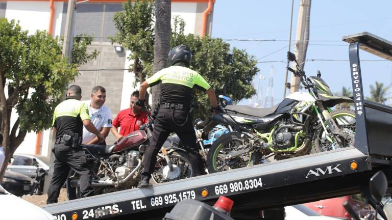 Elementos de la Policía Turística apoyan a tránsitos en el decomiso de motos por estar estacionadas sobre la banqueta.