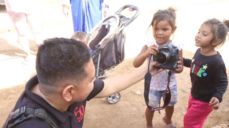 Lola agarra la cámara para tomarle fotos al fotógrafo de Noroeste, mientras Natalia le dice cómo hacerle.