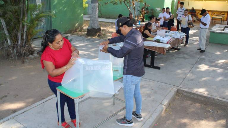 Funcionarios de casilla instalan las urnas y las mamparas.