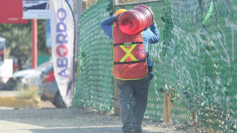 Trabajadores de la construcción transportan agua para mantenerse hidratados durante el trabajo.