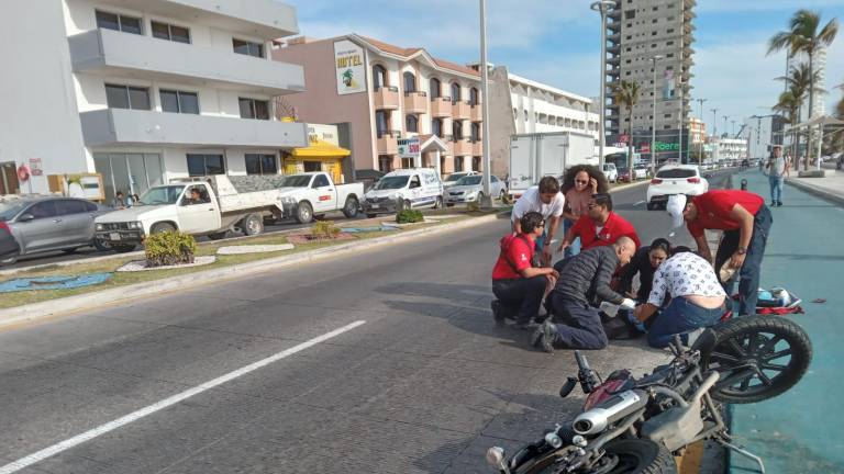 Le brindan los primeros auxilios al motociclista lesionado.