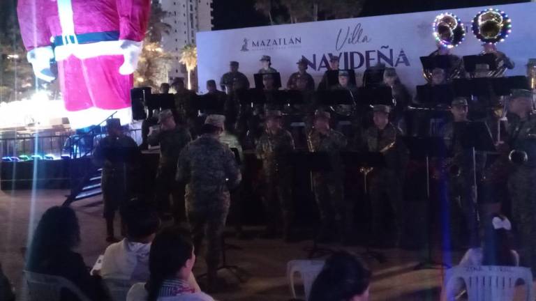 Ante decenas de asistentes, la Banda de Música de la Tercera Región Militar interpretó villancicos y música regional en la Villa Navideña del Parque Central.