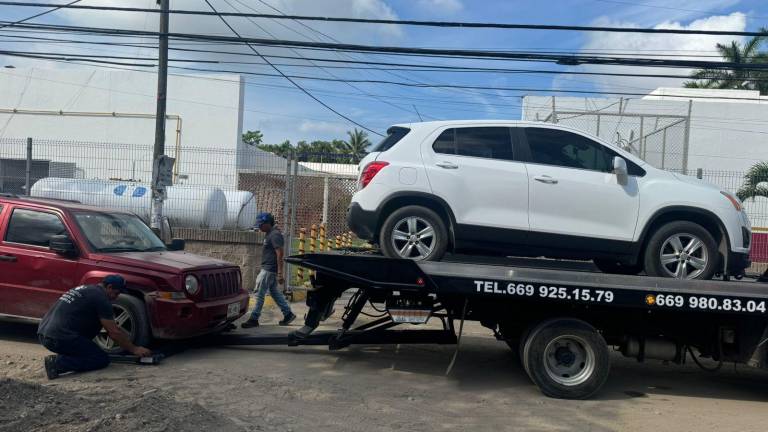 Con grúas de plataforma retiran vehículos mal estacionados afuera de la Clínica del ISSSTE en Mazatlán.