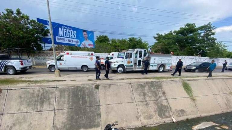 Elementos de Bomberos Veteranos y policías acuden a prestar auxilio al motociclista que cayó al canal pluvial.