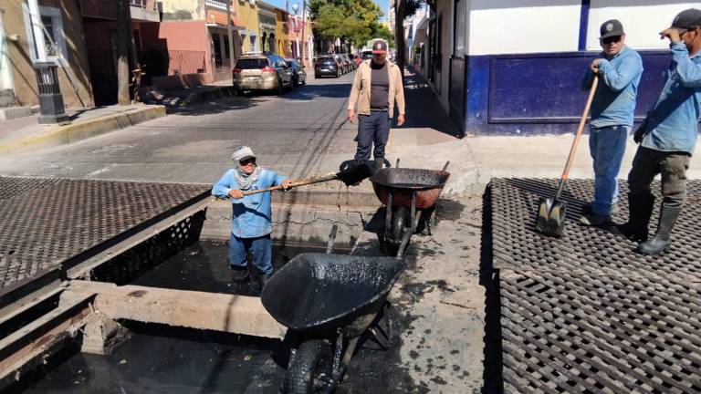 Una cuadrilla de 10 trabajadores sacan el lodo en una parte de la rejilla para en la otra permitir el paso de los vehículos .