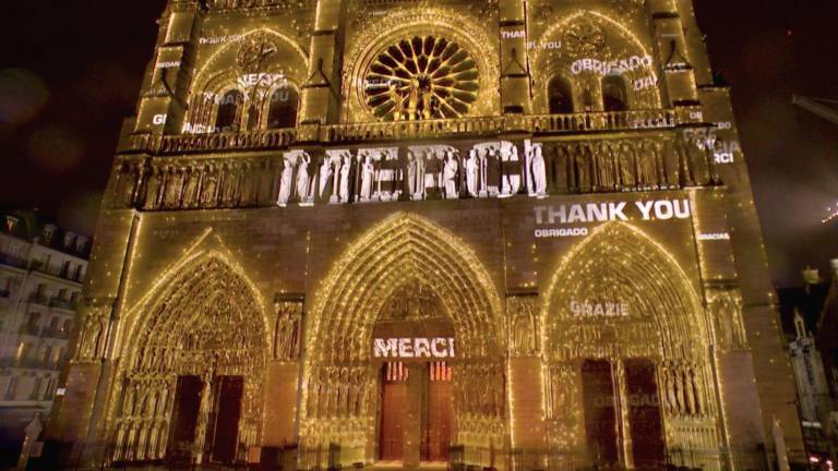 “Merci” es la enorme escritura luminosa proyectada en la fachada de la Catedral de Notre Dame.