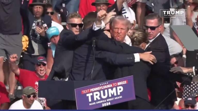 Donald Trump levanta el puño hacia la multitud momentos antes de ser sacado del escenario por agentes del Servicio Secreto en Pensilvania.