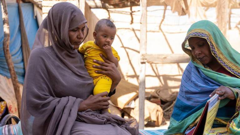 Una madre con su hija de 9 meses recibe apoyo de una concejal en el estado de Kassala, Sudán.