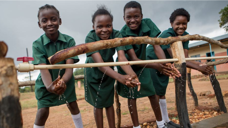 Alumnos se limpian las manos en un punto de lavado de manos recién construido en una escuela primaria del distrito de Pemba, Zambia.