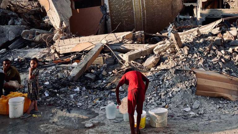 Una persona colecta agua entre las ruinas en Gaza.